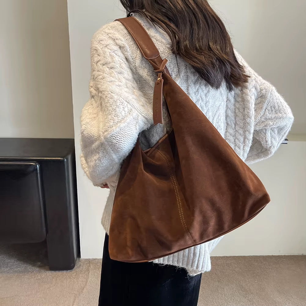 Woman styling a chic brown suede bag, effortlessly complementing her outfit with a timeless and elegant accessory – available at Shop Style Edit.