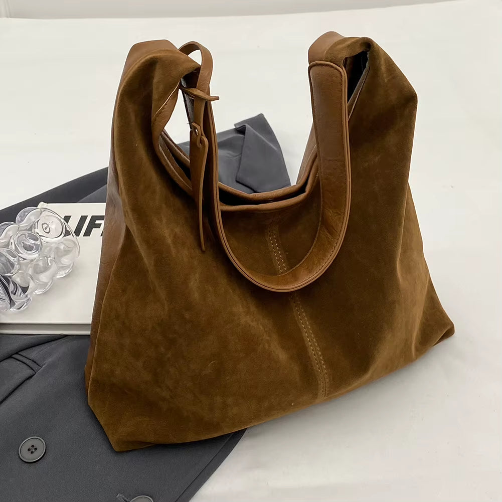 Woman styling a chic brown suede bag, effortlessly complementing her outfit with a timeless and elegant accessory – available at Shop Style Edit.
