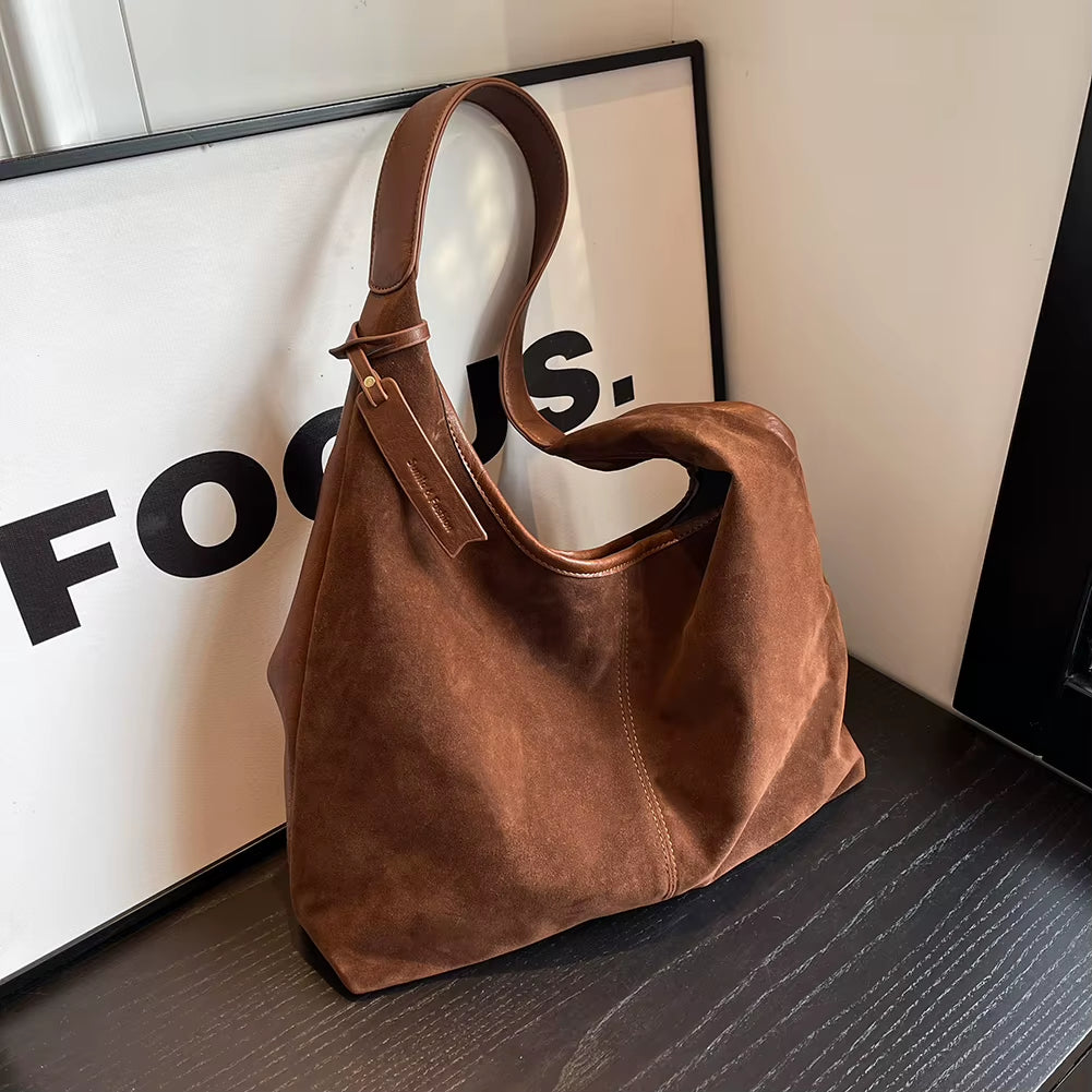 Woman styling a chic brown suede bag, effortlessly complementing her outfit with a timeless and elegant accessory – available at Shop Style Edit.