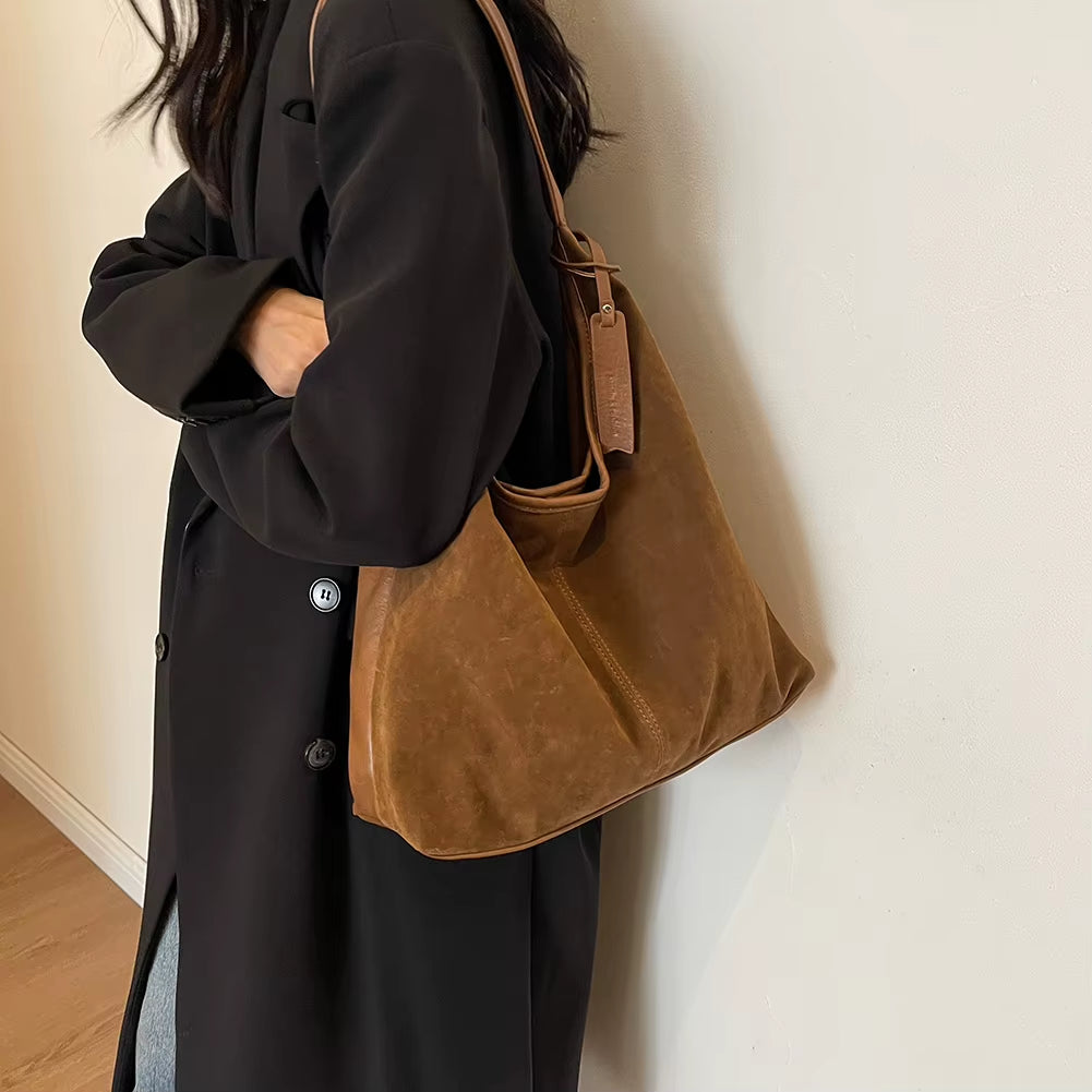 Woman styling a chic brown suede bag, effortlessly complementing her outfit with a timeless and elegant accessory – available at Shop Style Edit.