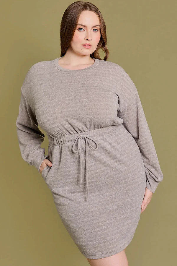 Plus size model wearing a taupe stripe drawstring waist mini dress with long sleeves and a relaxed fit.